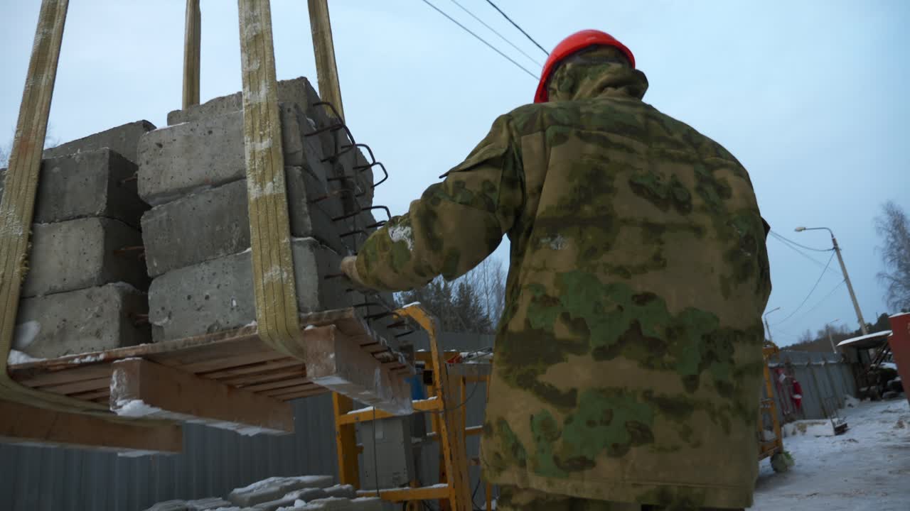 trabajador de la construcción que levanta piedras de pavimentación usando una grúa en invierno