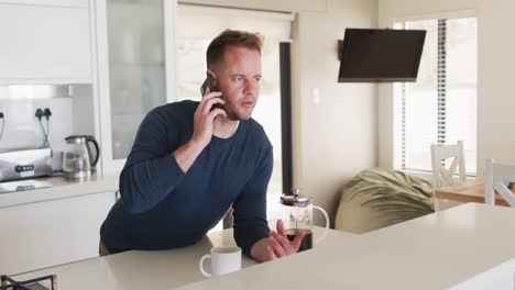 caucasian man talking on a smartphone in kitchen