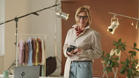 senior female photographer holding camera and smiling