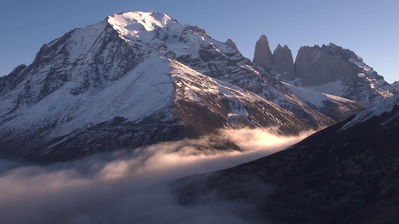 Volo aereo sopra le nuvole accanto alle montagne della Regione di Magellano durante l'ora d'oro