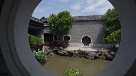 Oriental-Chinese-garden-and-lake,-seen-through-a-round-window