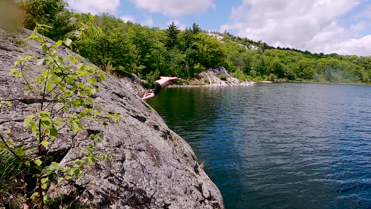 Vidéo de stock Premium - Jeune homme blanc saute du rocher dans le lac ...