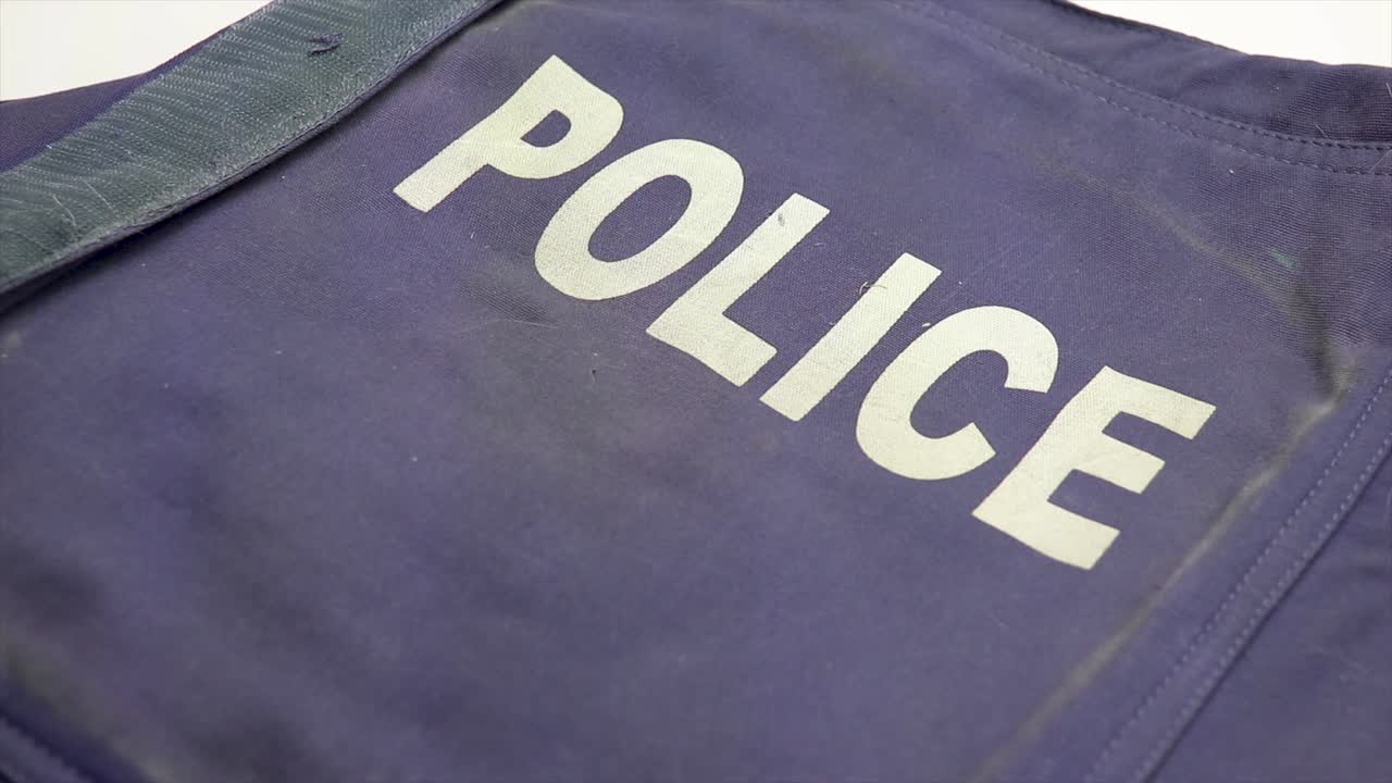 검은색 총기 손 권총이 경찰의 방탄 안전 조끼 위에 배치되어 있습니다.