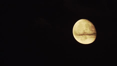 Cerrar-La-Luna-Llena-En-Ascenso-Detrás-De-Una-Pequeña-Nube,-Cielo-Nocturno-Negro