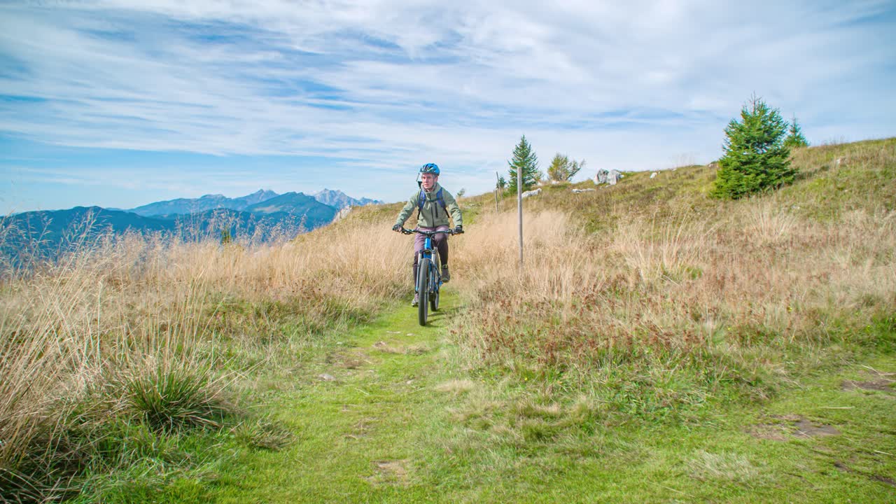 Couple Mountain Biking Across Grassland On Mount St. Ursula. Slow Motion, Follow Shot