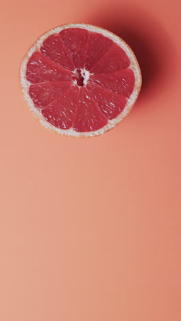 vertical video of halved red grapefruit with copy space over red background