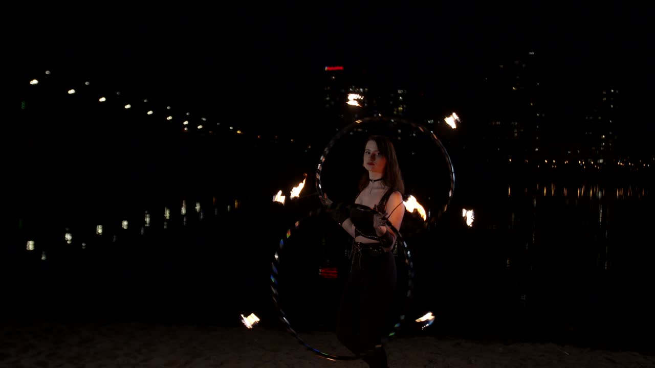 artista femenina retorciendo aros de fuego durante un espectáculo de fuegos artificiales