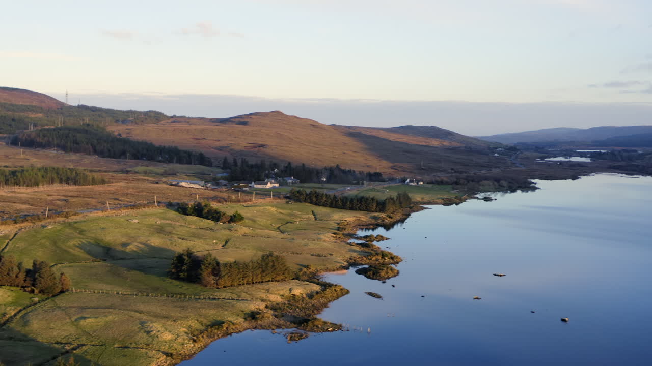 Aerial tracking right to establish Lough Bofin at midday, where sunlit waters create dazzling reflections against the vibrant landscape, Connemara, Galway, Ireland
