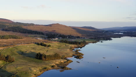 aerial tracking right to establish lough bofin at midday, where sunlit waters create dazzling reflections against the vibrant landscape, connemara, galway, ireland