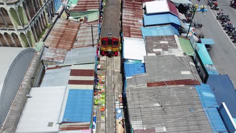 a drone shooting following a train and over the mae klong railway market market