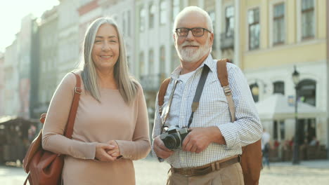 Porträtaufnahme-Der-Gut-Aussehenden-Grauhaarigen-Touristen,-Die-An-Einem-Sonnigen-Tag-In-Der-Stadt-Stehen-Und-In-Die-Kamera-Lächeln