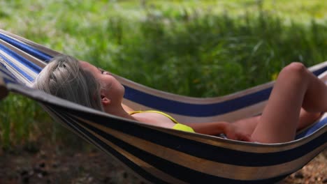 a beautiful sexy young female wearing bikini and relaxing on the hammock on a windy day