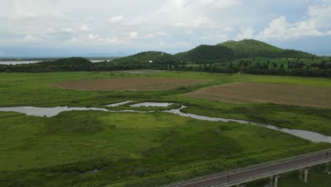 a drone footage of a gorgeous scenery revealing an elevated railway, hills and lake at the distance, in saraburi, thailand.