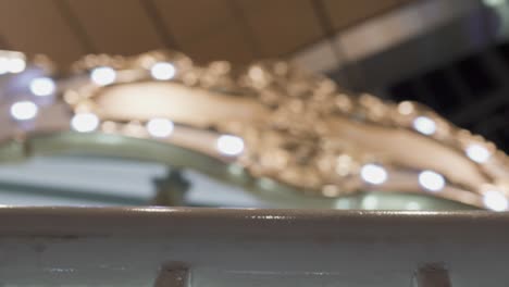 spinning carousel in the amusement park at night. the focus is on the front and the background is blurred. the focus is on the metal railings. look up.