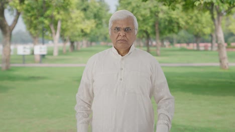angry indian old man looking at the camera in park