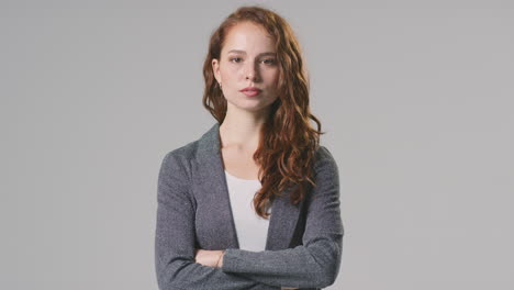 retrato de estudio de una joven mujer de negocios seria con los brazos cruzados contra un fondo plano