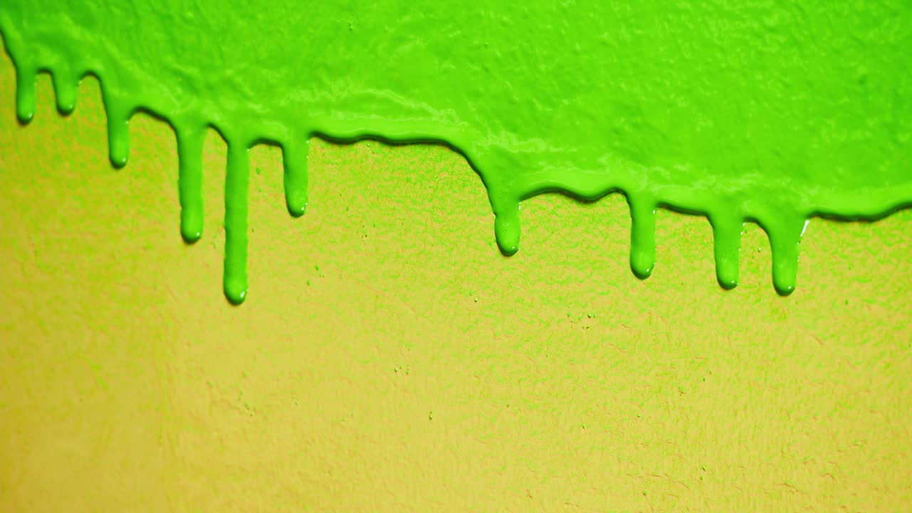 Vibrant Green Paint Dripping Slowly on Yellow Background