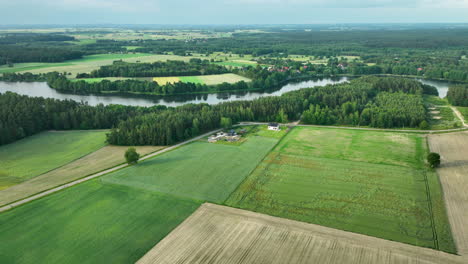 Luftaufnahme-Eines-Ausgedehnten-Ackerlandes-Mit-Einem-Fluss,-Der-Sich-Durch-Die-Landschaft-Schlängelt