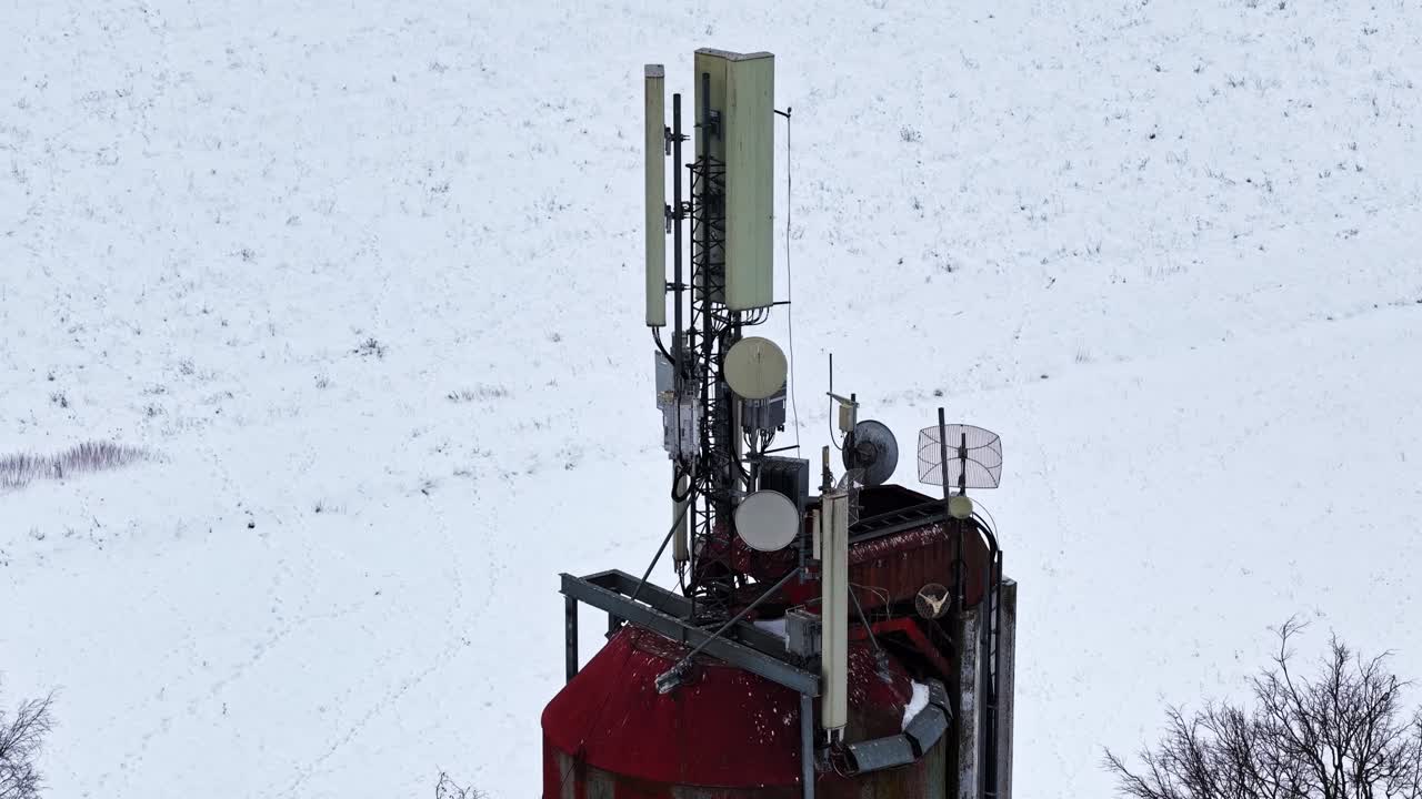 通信アンテナとディッシュを備えた給水塔が、白い雪原の上にそびえ立つ。