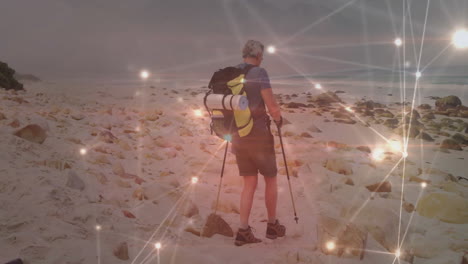 hiker using trekking poles walking across sandy beach, showing technology network connections