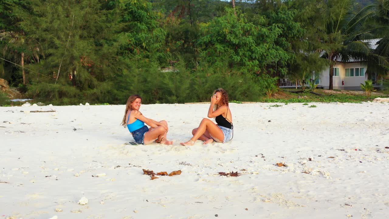 Giovani donne infantili che giocano a sasso carta forbice sulla spiaggia sabbiosa