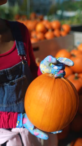 mujer sosteniendo una calabaza en un puesto de la granja