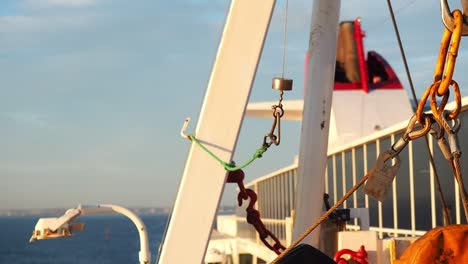 a tight shot of various rigging, chains, and structures on the side of a boat