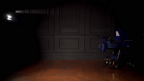 blue baby pram in dark room with the only light lamp. modern stroller being pushed from one side of the room to another.