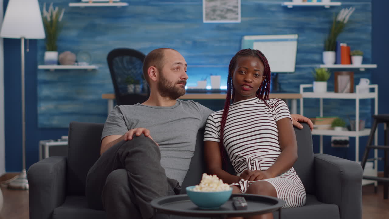 Casal inter-racial acenando para a câmera da videochamada e conversando