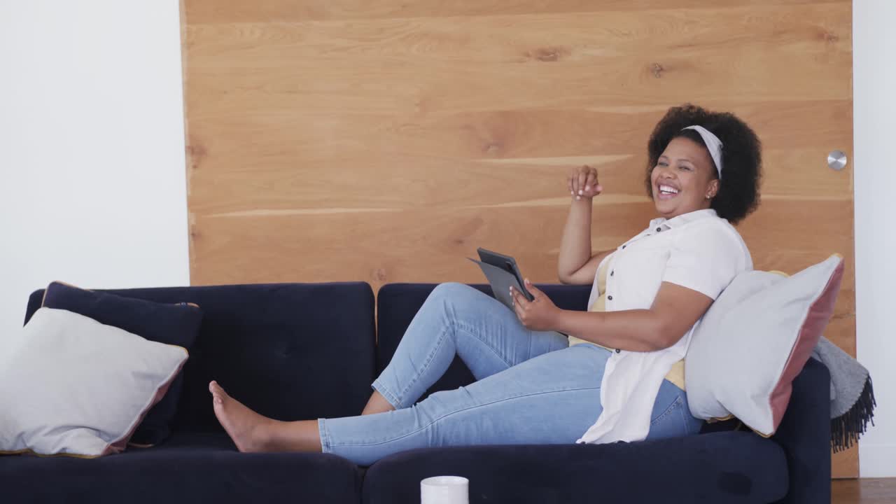 Happy african american plus size woman using tablet, unaltered, copy space, slow motion