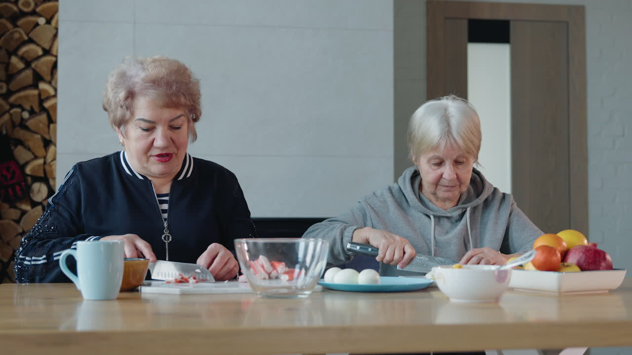 두 명의 고령 여성이 집에서 러드를 준비하고 있습니다.