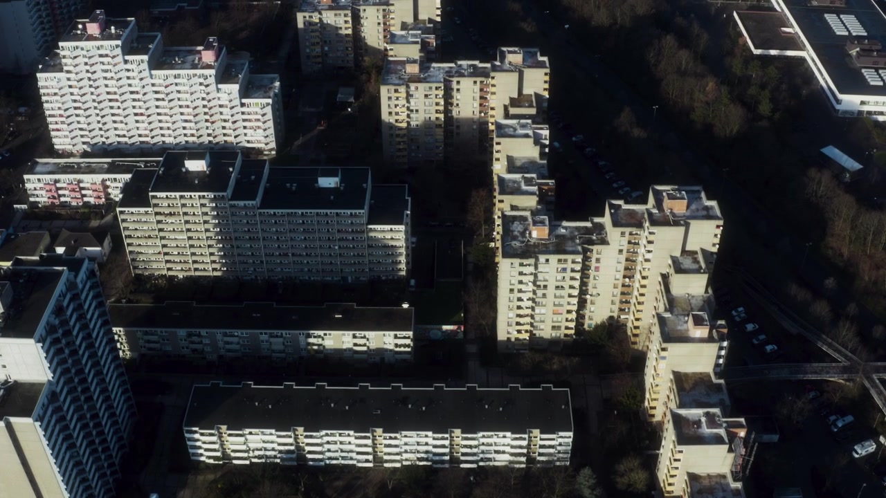 A luz do sol reflete nos blocos de apartamentos de Colônia enquanto um drone avança em altitude