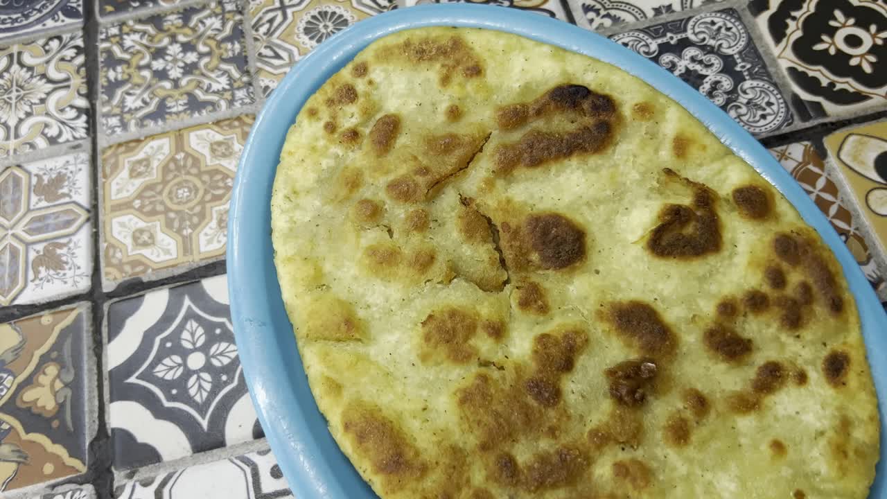 Desenli vintage fayanslar önünde mavi bir tabakta servis edilen geleneksel bir huarache'nin yakın çekimi.