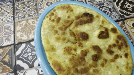 close-up of a traditional huarache served on a blue plate against patterned vintage tiles