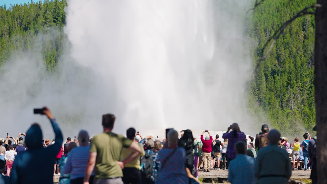Tourists gather to watch a powerful geyser eruption at Yellowstone National Park