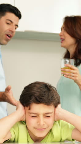 un niño molesto cubriéndose las orejas mientras sus padres pelean