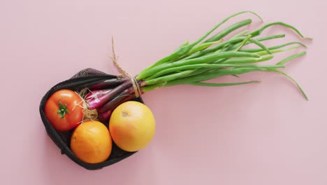 Video-Von-Frischem-Obst-Und-Gemüse-In-Einer-Schwarzen-Tüte-Auf-Rosa-Hintergrund