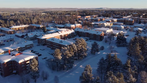 Aerial-flying-forward-over-snow-covered-houses-in-Arvidsjaur,-Lapland