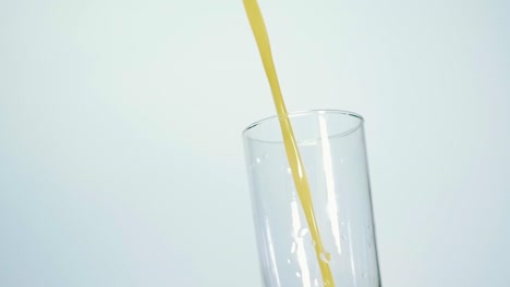 Slow-Motion-Shot-of-Fresh-Orange-Juice-Being-Poured-in-a-Glass-on-white-background-Close-up-Shallow-depth-of-field