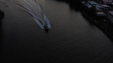 aerial drone shot over a small fast boat coming in under my drone's camera with the evening sunset and new york city skyline in the background