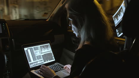 back view of businesswoman working on laptop in car