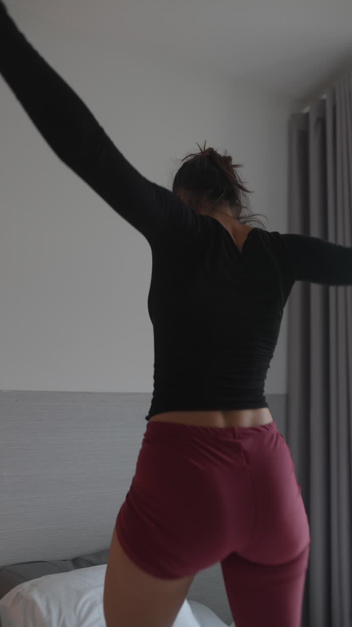 mujer bailando y jugando con almohada en el dormitorio