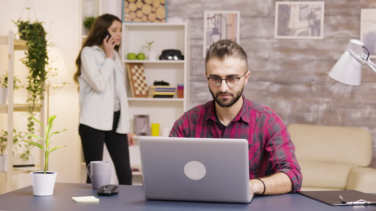 Man working from home with woman in background