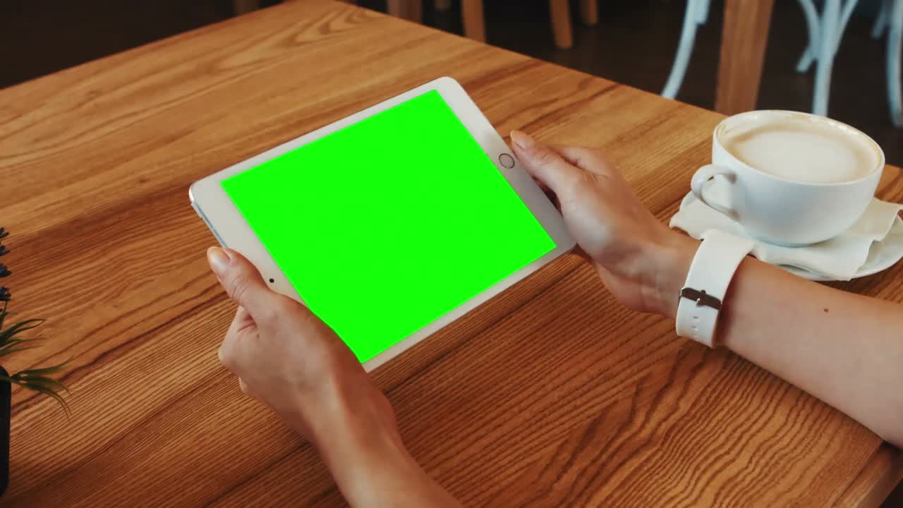 Kvinde bruger digital tablet, mens hun drikker kaffe