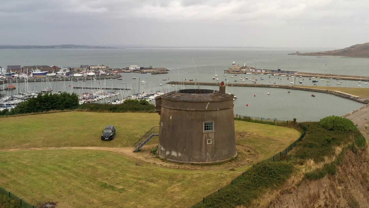 Långsam högerrotation runt Martello Tower i Howth, norra Dublin, Irland, med hamn i bakgrunden under en mulen dimmig dag