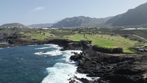 aerial dolly along jagged basalt cliffs lined with scenic golf course in tenerife