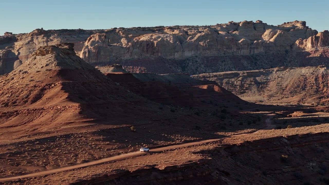 Veduta aerea di un veicolo bianco che si muove su una strada nel deserto nel paesaggio dello Utah rurale, USA. Ripresa con drone.