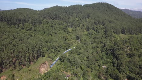 Antena:-Tren-De-Pasajeros-Serpentea-A-Lo-Largo-De-La-Pista-De-La-Montaña-Boscosa-Verde