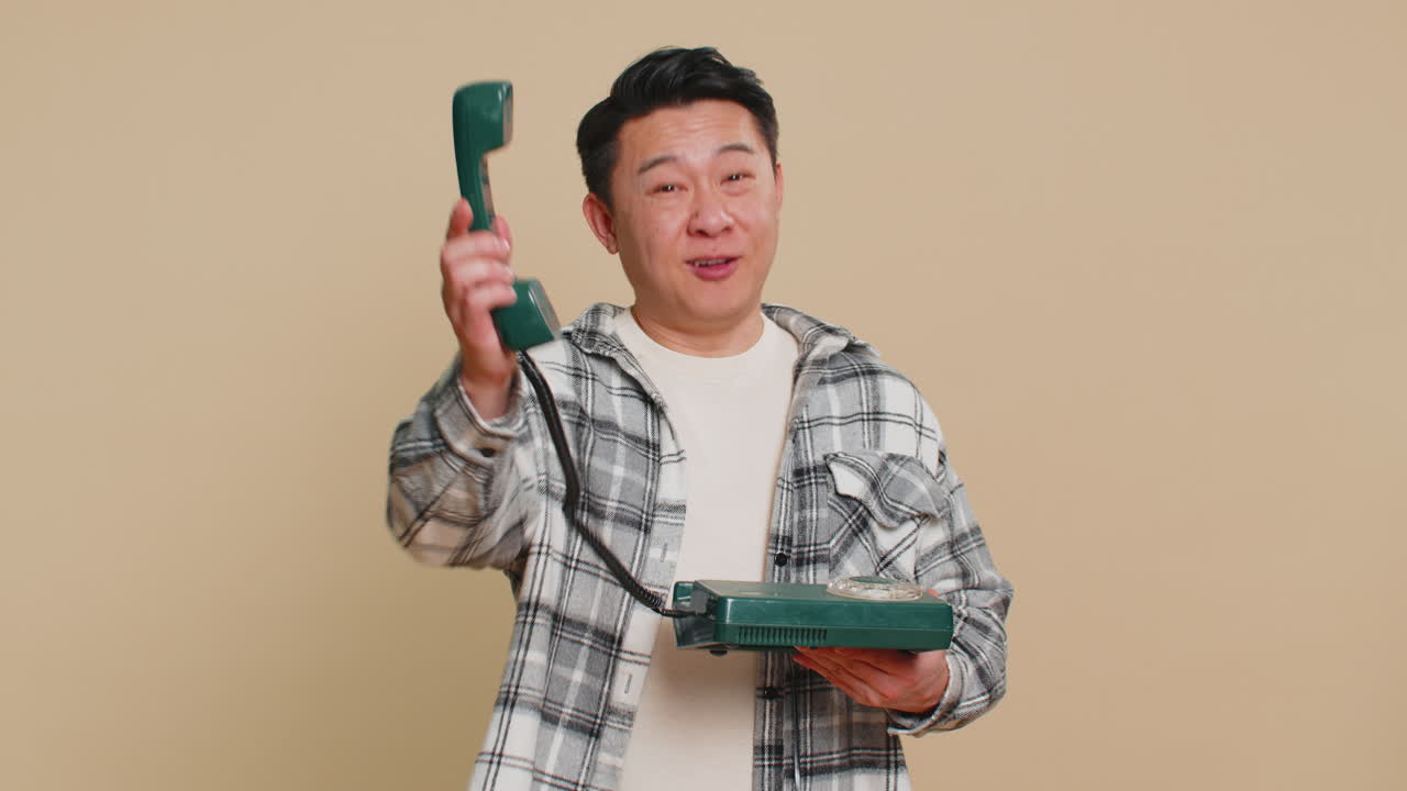 Asian man talking on wired landline vintage telephone advertising proposition of conversation