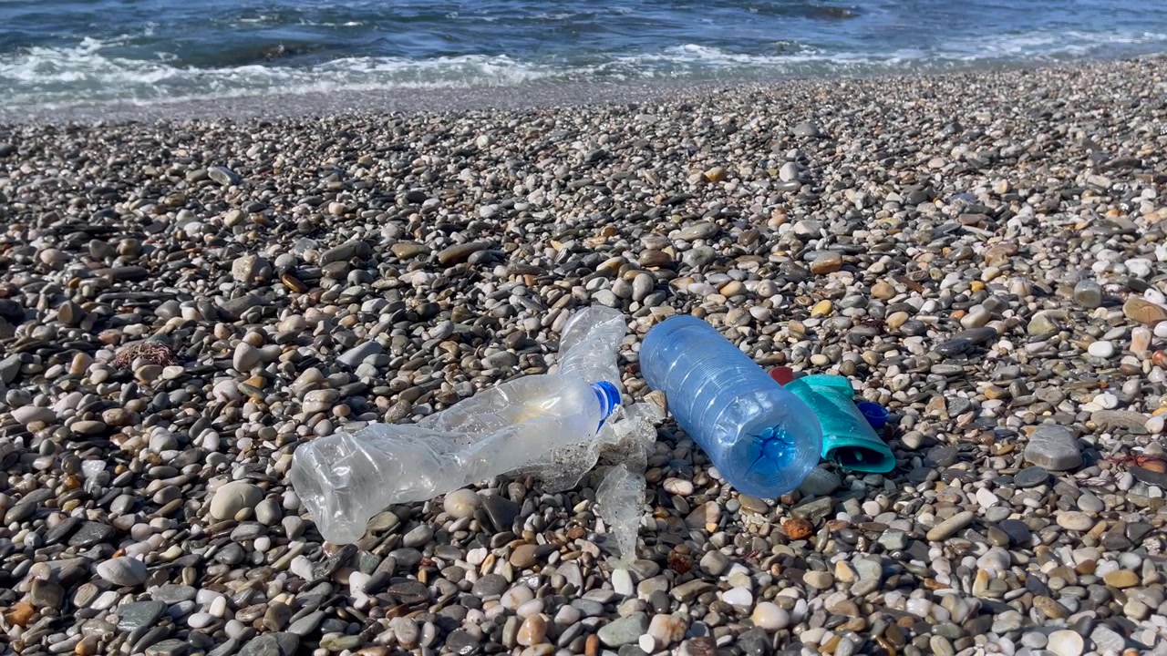 Bottiglie di plastica e detriti su una spiaggia rocciosa vicino alle onde dell'oceano